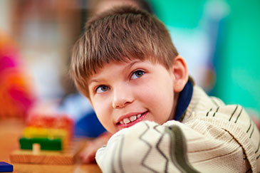 A young boy smiles happily while seated at a table, exuding joy and contentment.