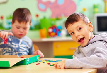Two young boys engaged in play with colorful toys inside a bright classroom setting.